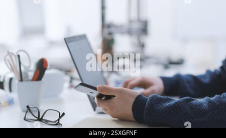 Student working with a computer and a smartphone in the lab, hands close up: science, technology and education concept Stock Photo