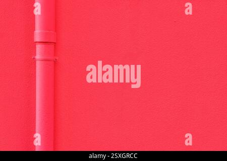 Red wall texture and a red downspout gutter of a house. Photo suitable for background or design backdrop. Copy space for graphic design. Stock Photo
