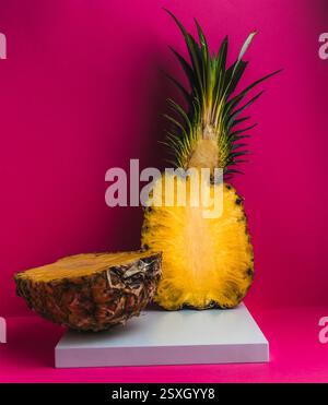 Freshly sliced pineapple on display with vibrant pink background highlighting juicy interior in modern setting Stock Photo