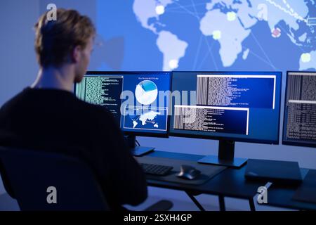 Back View in the Cyber Security Control Center Operator Working. Multiple Screens Showing Technical Data and Alerts. Stock Photo