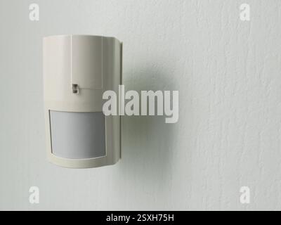 Modern motion sensor on wall indoors Stock Photo