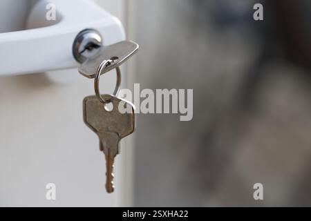 A close-up of a key inserted in a door lock, with a blurred background. Stock Photo