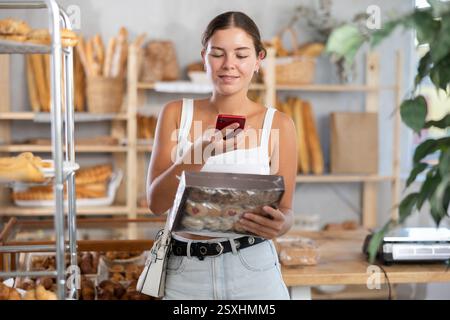 Woman checks calories in cookies using app on phone Stock Photo
