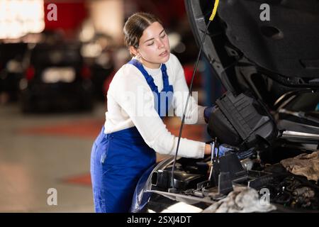 Female mechanic changing air filter in car engine Stock Photo