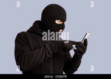 Masked villain touching a smart phone screen Stock Photo