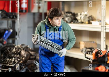 Young auto mechanic repairing an engine in garage Stock Photo