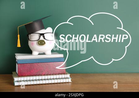 Scholarship. Piggy bank with graduate hat, eyeglasses and books on table near green chalkboard. Speech cloud with word Stock Photo