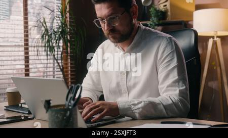 Busy Caucasian man male developer company employer guy working manager worker using laptop tech executive broker typing computer in office agency Stock Photo