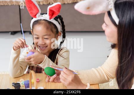 Easter fun for all. A mother and child engage in a joyful Easter tradition, painting eggs in vibrant colors with a paintbrush and decorating a festive Stock Photo