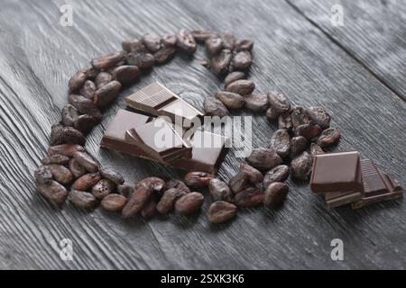 Cocoa beans arranged in a heart on a dark wooden background Stock Photo