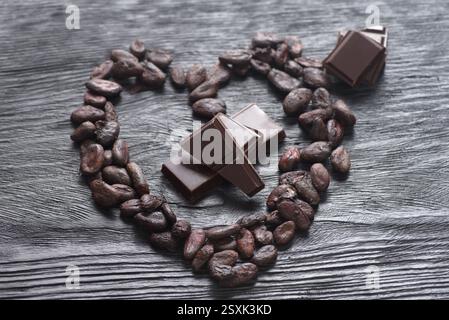 Cocoa beans arranged in a heart on a dark wooden background Stock Photo