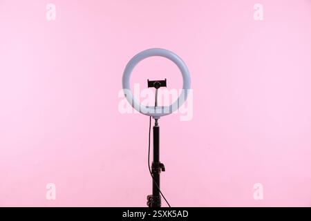 Ring lamp with holder for smartphone against pink background Stock Photo