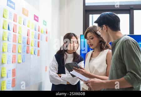 brainstorming session, using sticky notes on a task board (kanban) to organize ideas and workflow in a modern office Stock Photo