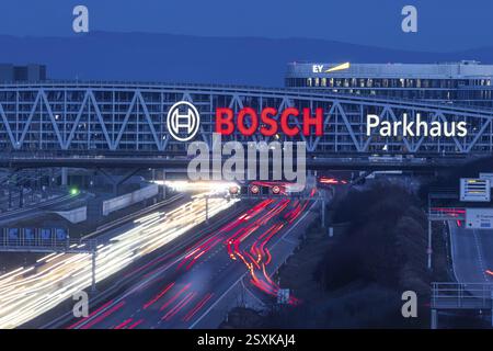 A8 motorway at Stuttgart Airport in the evening. Heavy traffic, lanes of light. Modern architecture of Messe Stuttgart with multi-storey car park abov Stock Photo