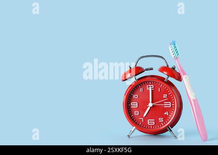 Red alarm clock and toothbrush on blue background Stock Photo