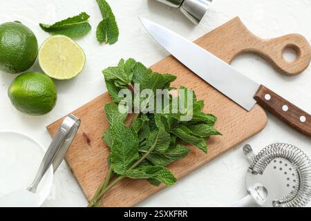 Wooden cutting board, knife and ingredients for preparing mojito on white background, closeup Stock Photo