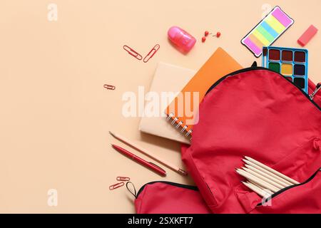 School backpack with different stationery supplies on beige background Stock Photo