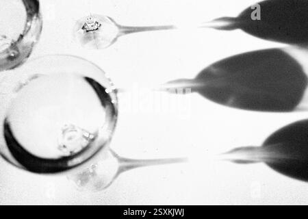 Fancy retro drinking glasses casting hard shadows on background. Grunge and noise effect applied, retro vintage style. Black and white image. Image co Stock Photo