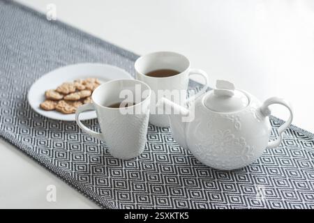 White ceramic teapot, tea and cookies on the table Stock Photo