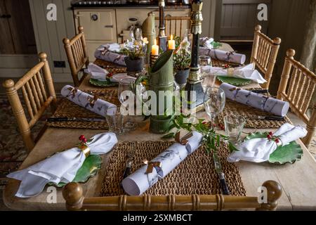 Christmas crackers and napkins at place settings with lit candles in renovated East Sussex Tudor farmhouse dating from 1540, England, UK. Stock Photo