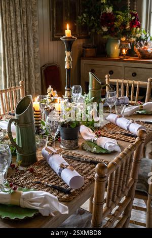 Christmas crackers and napkins at place settings with lit candles in renovated East Sussex Tudor farmhouse dating from 1540, England, UK. Stock Photo