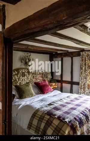 Coordinated fabrics in beamed bedroom of renovated East Sussex Tudor farmhouse dating from 1540, England, UK. Stock Photo