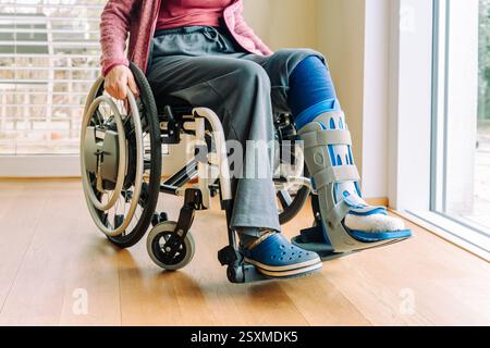 Detail or woman in a wheelchair with leg brace after sport injury Stock Photo