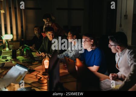 Multiracial team collaborates on project during late night office meeting Stock Photo