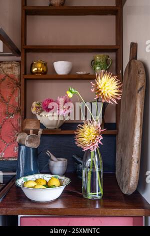 Cut flowers and shelving with chopping board in kitchen of Chalford weavers cottage in the Cotswolds, Gloucestershire, England, UK. Stock Photo