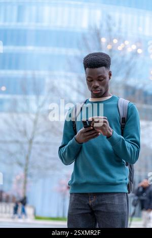 Focused student using smartphone in front of modern building Stock Photo