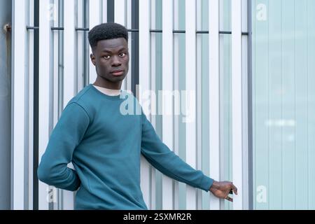 Portrait of a stylish young man posing near a modern glass and steel structure Stock Photo