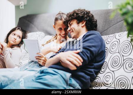 Friends sitting on couch sharing a laugh while studying together Stock Photo