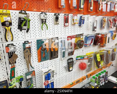 Various tools displayed on pegboard in hardware store aisle. Stock Photo