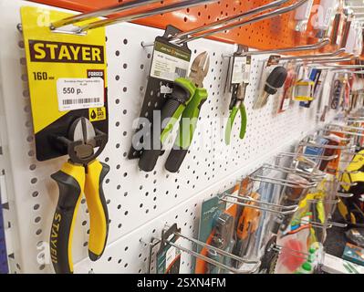 Assorted handheld tools displayed on pegboard in hardware store. Stock Photo