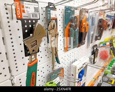 Assorted hand tools displayed on pegboard in hardware store aisle. Stock Photo