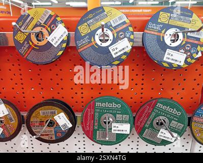 Assorted metal cutting discs display on orange pegboard in hardware store. Stock Photo
