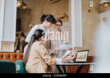 Three businesswomen collaborating on documents during a meeting in a stylish office Stock Photo