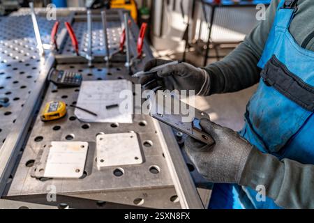 Metalworker marking measurements on metal plate in workshop Stock Photo