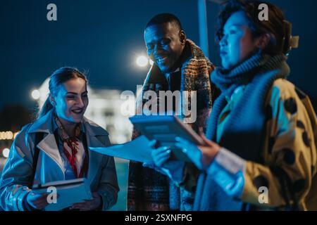 Multiracial people collaborating outdoors during nighttime Stock Photo