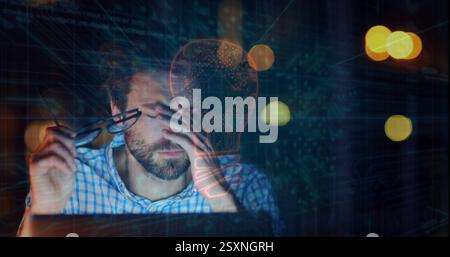 Holding glasses and looking at laptop, man with beard over image of lightbulb Stock Photo