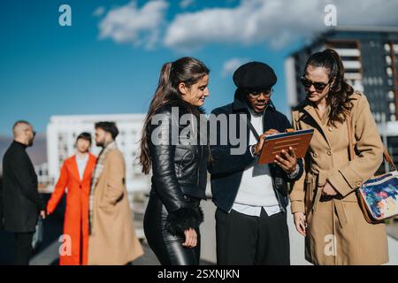 Diverse group of young professionals discussing business outdoors on a bright day Stock Photo