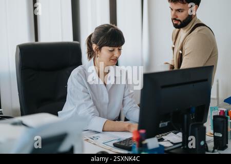 Office colleagues collaborating on a project while reviewing computer data Stock Photo