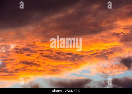 Heavy storm clouds lit underneath by setting sun - red sky at night. Stock Photo