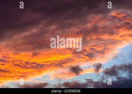 Heavy storm clouds lit underneath by setting sun - red sky at night. Stock Photo