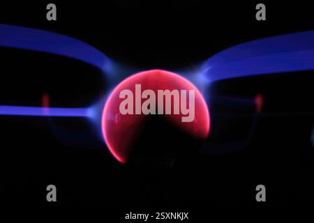 Pink and blue plasma filaments extending from a central sphere, creating a mesmerizing display of light and energy Stock Photo
