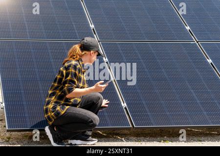 Female engineer at solar power plant using wireless technology to monitor panels Stock Photo