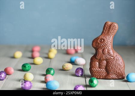 Cute chocolate Easter bunny and eggs over a green table. Selective focus with blurred background and copy space. Stock Photo