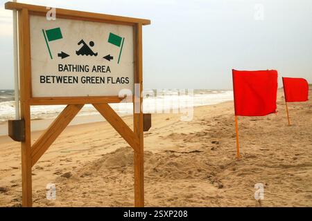 A sign warns ocean swimmers about where it is safe to go into the sea on s stormy summer day Stock Photo