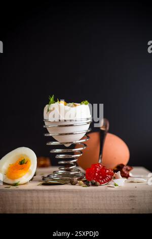 red caviar in a spoon and morning boiled egg for breakfast, isolated on black background. Stock Photo