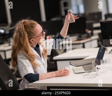 Caucasian woman in a medical gown doing laboratory experiments.  Stock Photo